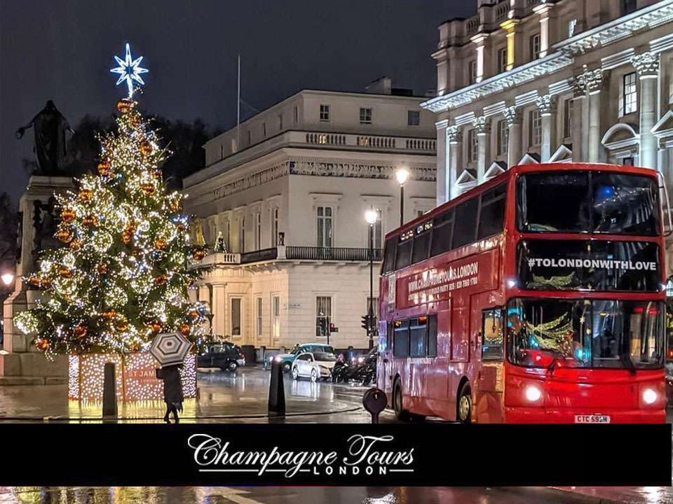 Red party bus beside a Christmas tree in London